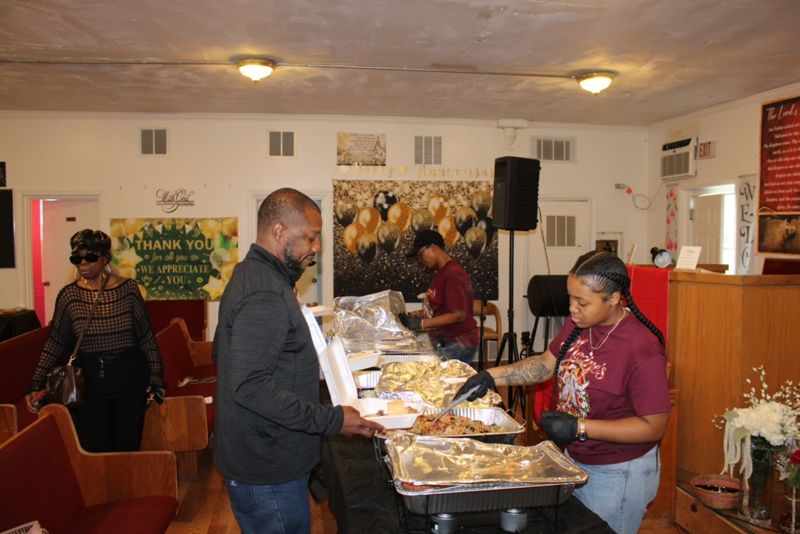 Guests moving along the serving table while a volunteer fills their plates.
