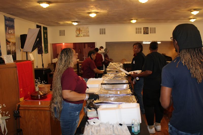 A volunteer handing a plated meal across the serving table to a guest.
